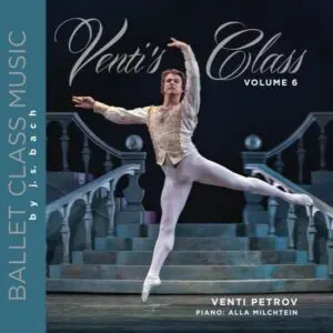A ballet dancer performs an elegant pose on stage in white costume.