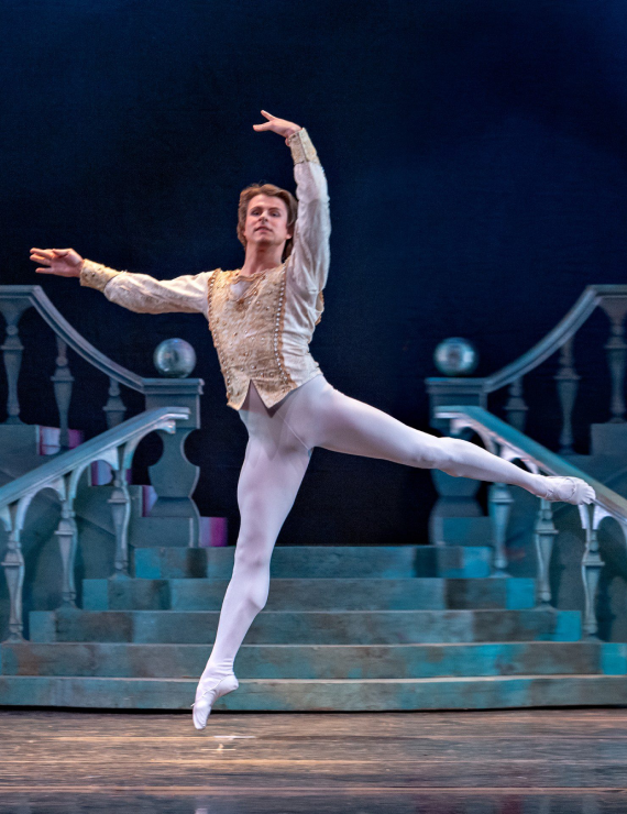 Ballet dancer performing a graceful leap on stage.